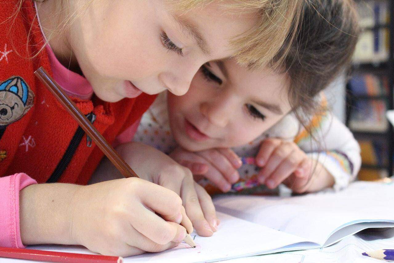 dwójka dzieci pisząca w zeszycie